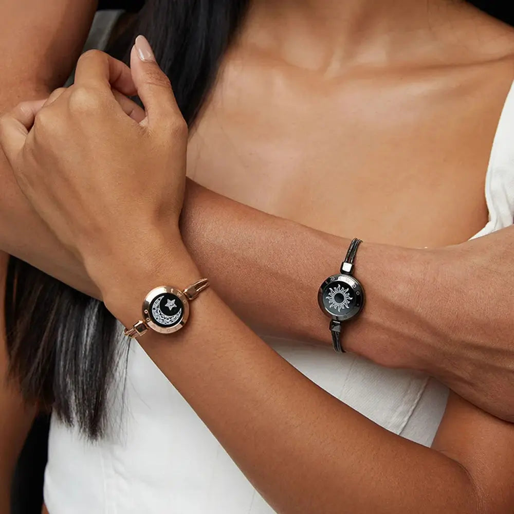 A couple holding hands, showcasing the EntangleTies™ bracelets — one with a crescent moon and star design and the other with a sun design, worn by the individuals.